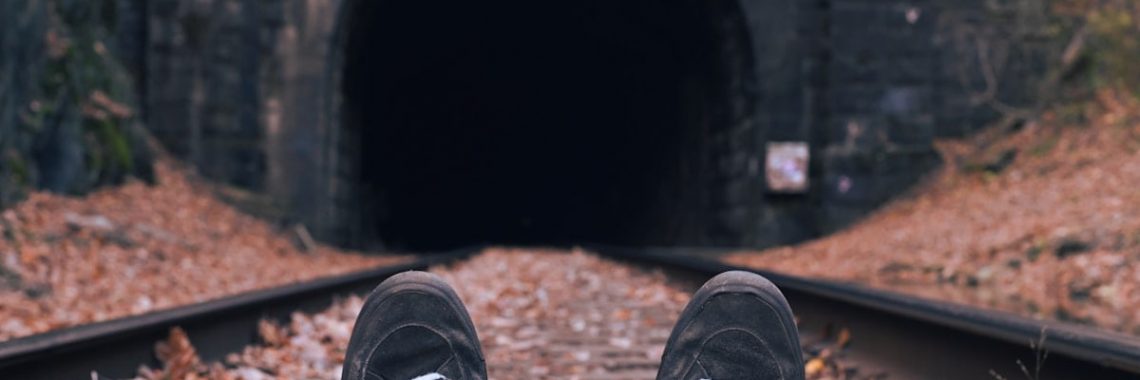 Train tracks lead towards a dark tunnel.